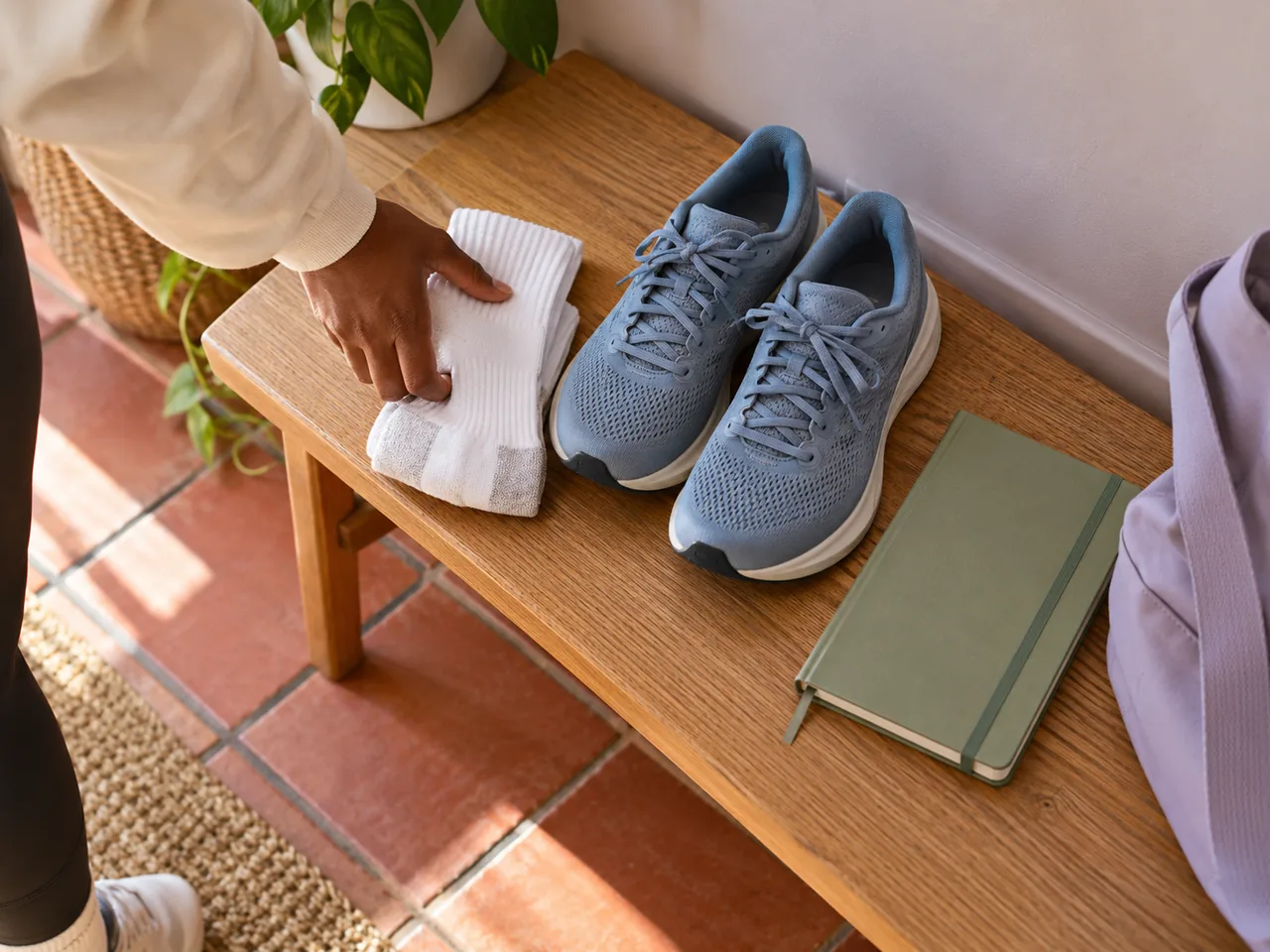 A hand placing fresh socks beside trainers and a closed notebook